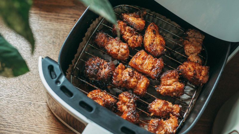 Air fryer basket pulled open with cooked chicken pieces inside