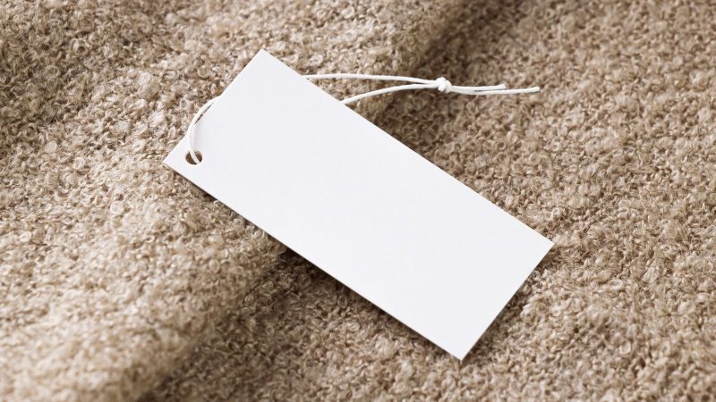 Blank white tag lying on textured fabric