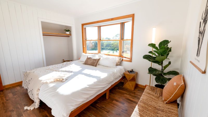 Bright bedroom with a white bed beside a window