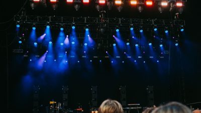 Concert stage lit in blue above a crowd at night