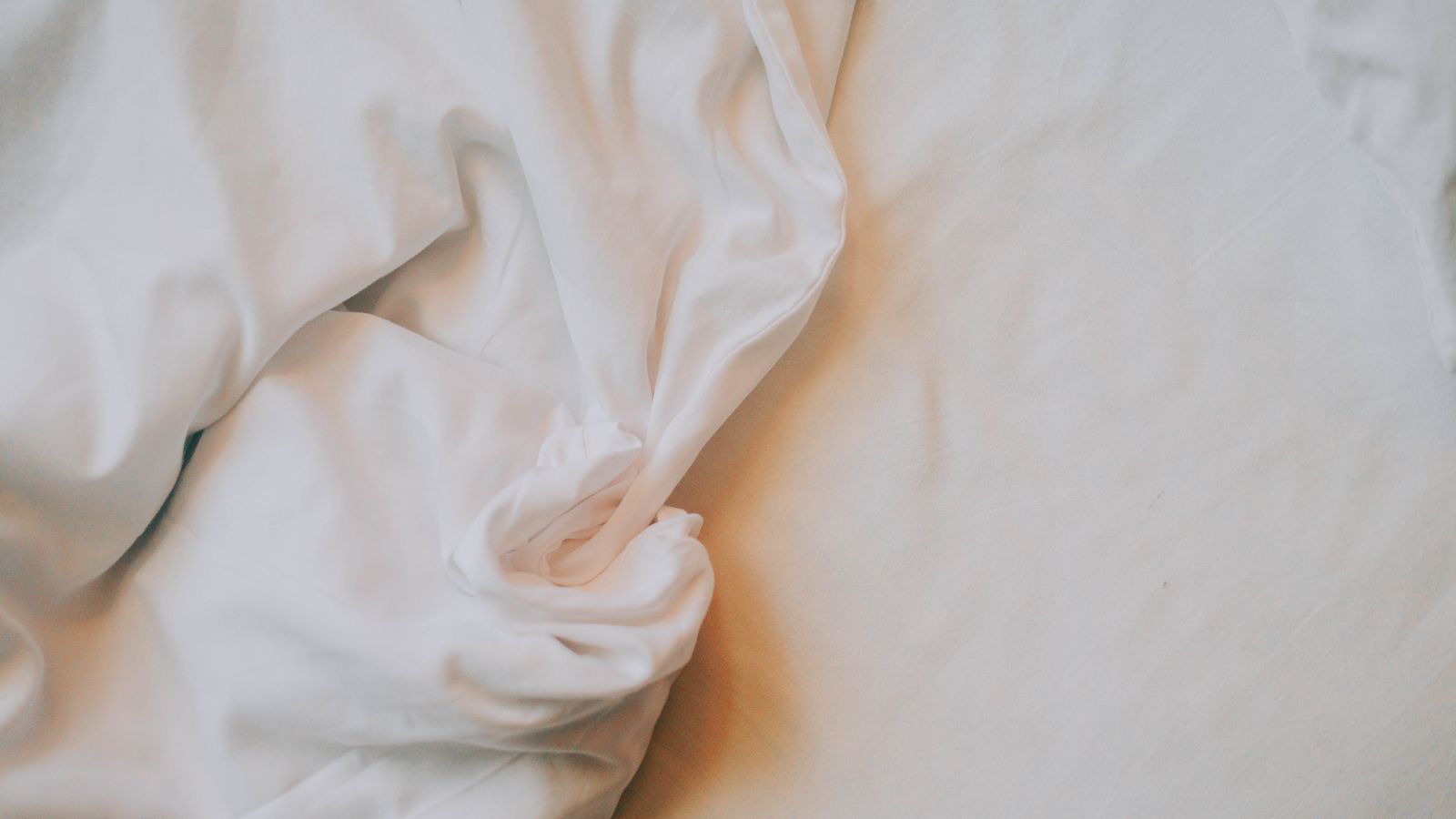 Crumpled white bed sheets in soft light