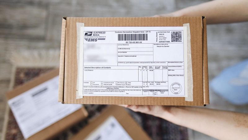 Hands holding a cardboard parcel with a shipping label