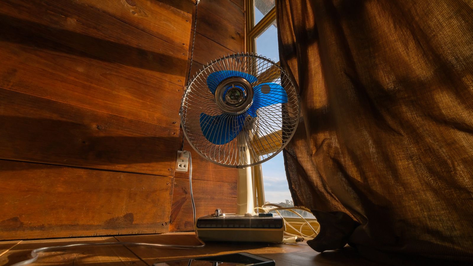 Electric fan beside a window in warm light