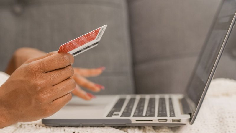Hands holding a payment card in front of a laptop