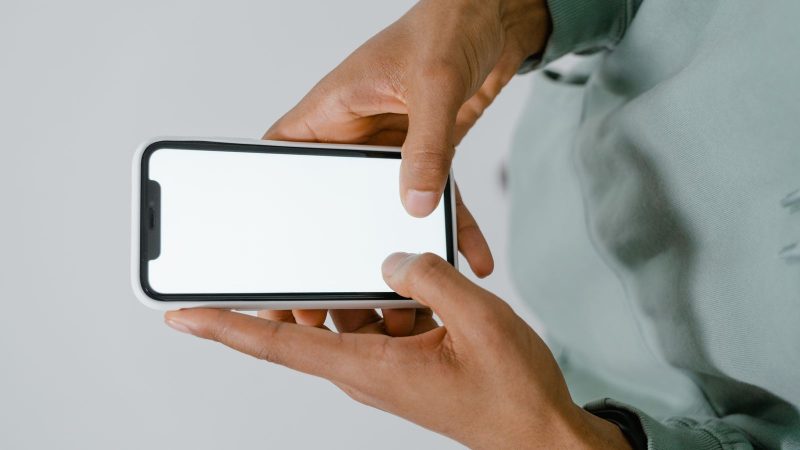Hands holding a smartphone with a blank screen