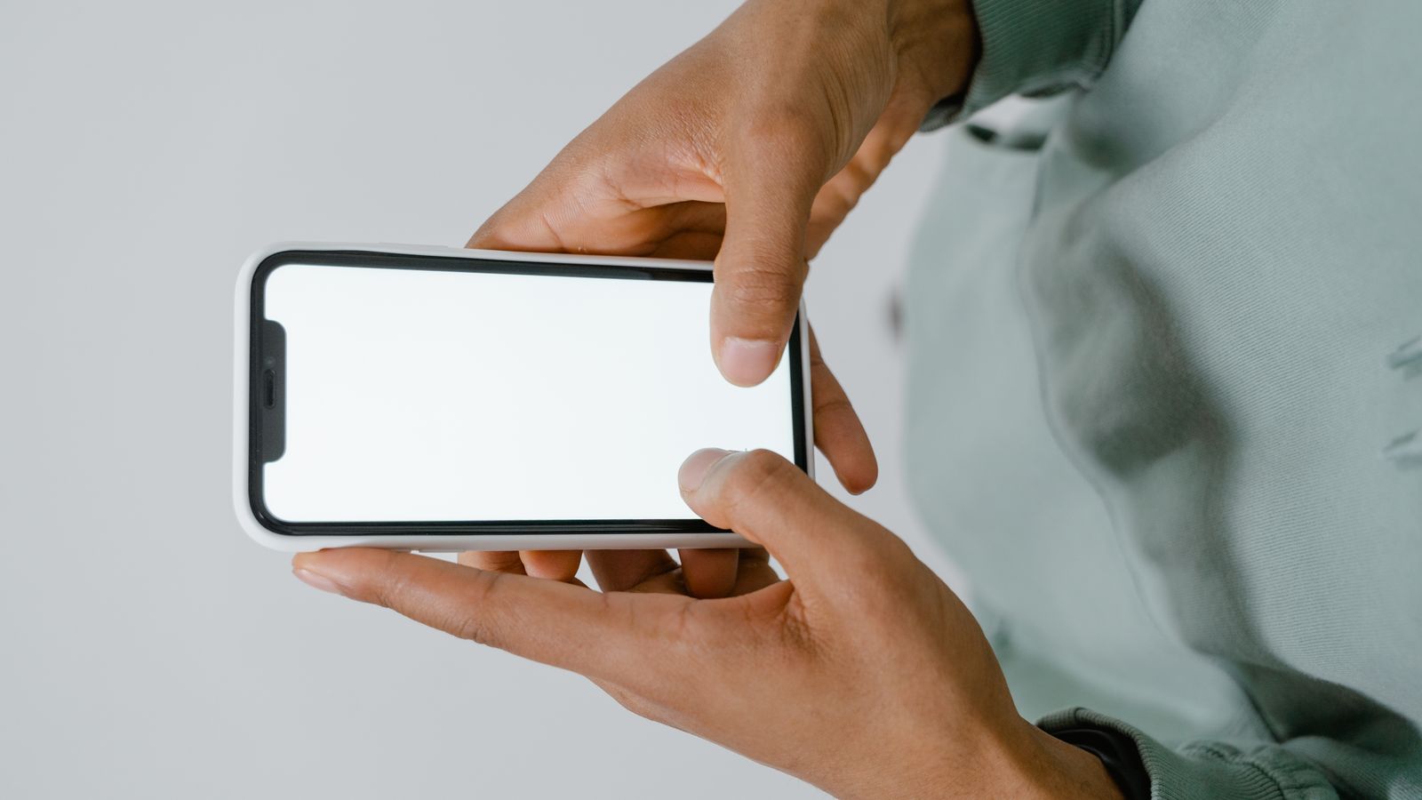 Hands holding a smartphone with a blank screen