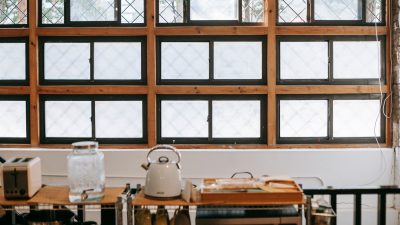 Kettle, toaster and glass jar on a kitchen shelf below a window
