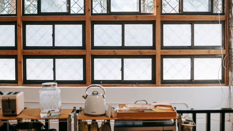 Kettle, toaster and glass jar on a kitchen shelf below a window