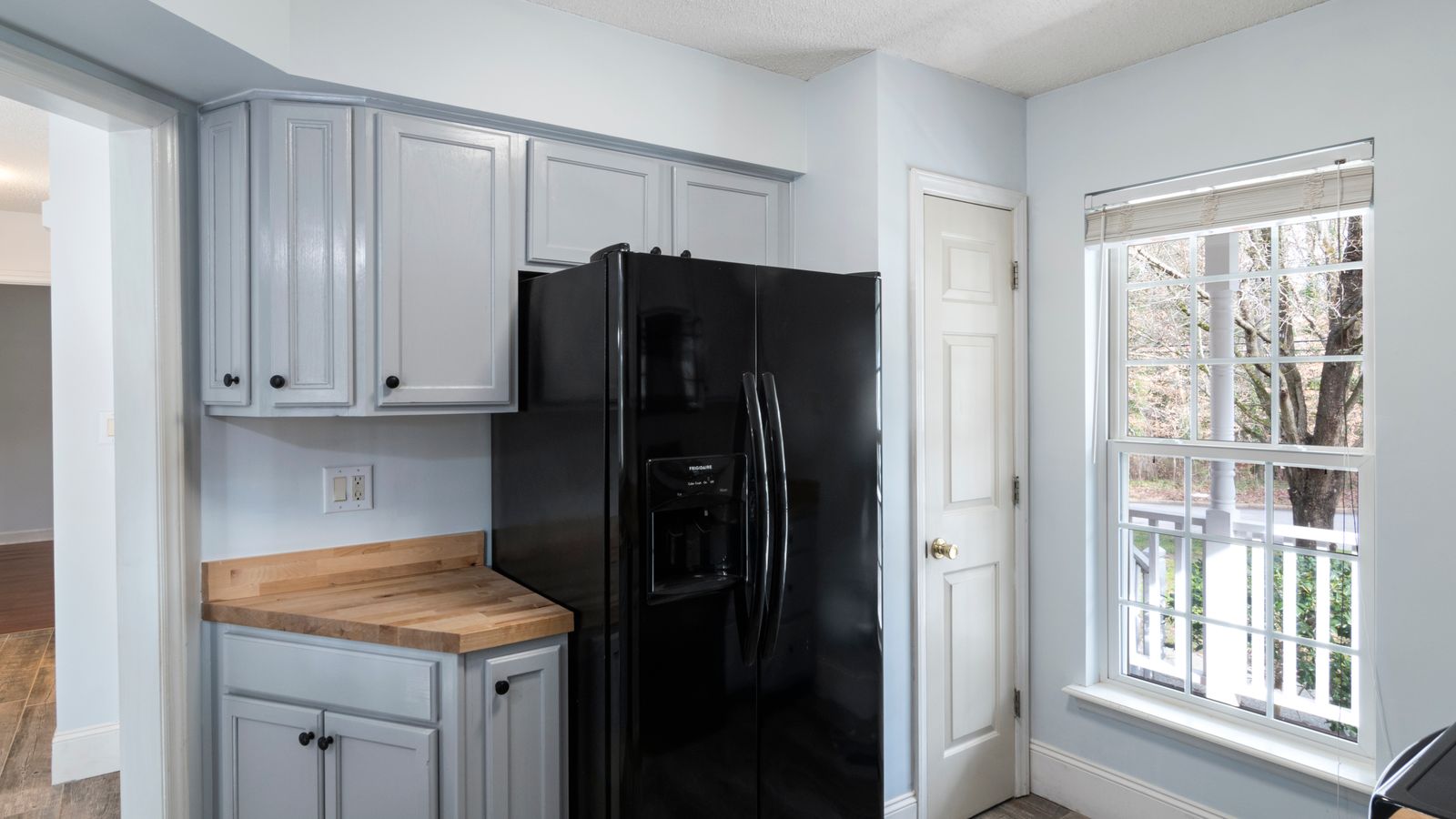 Kitchen with a black refrigerator beside a window
