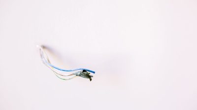 Loose electrical wires protruding from a white wall