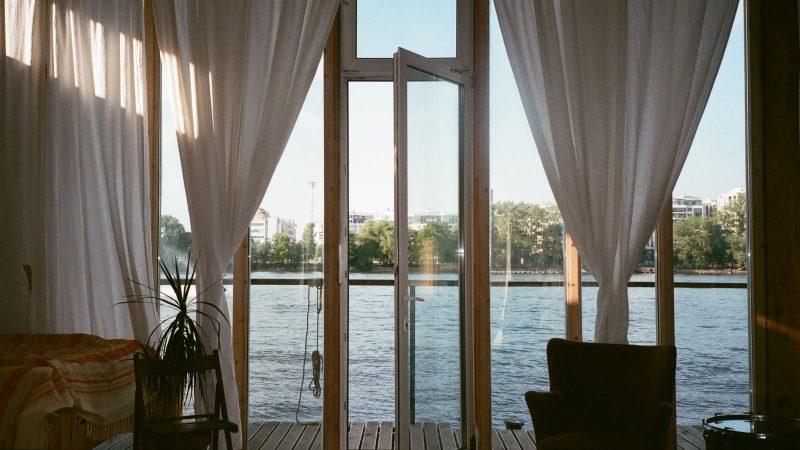 Open glass doors with white curtains letting air into a room