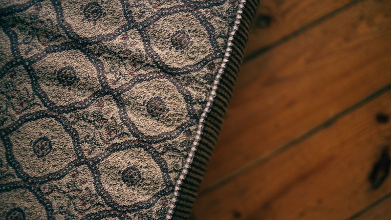 Corner of a patterned mattress on a wooden floor