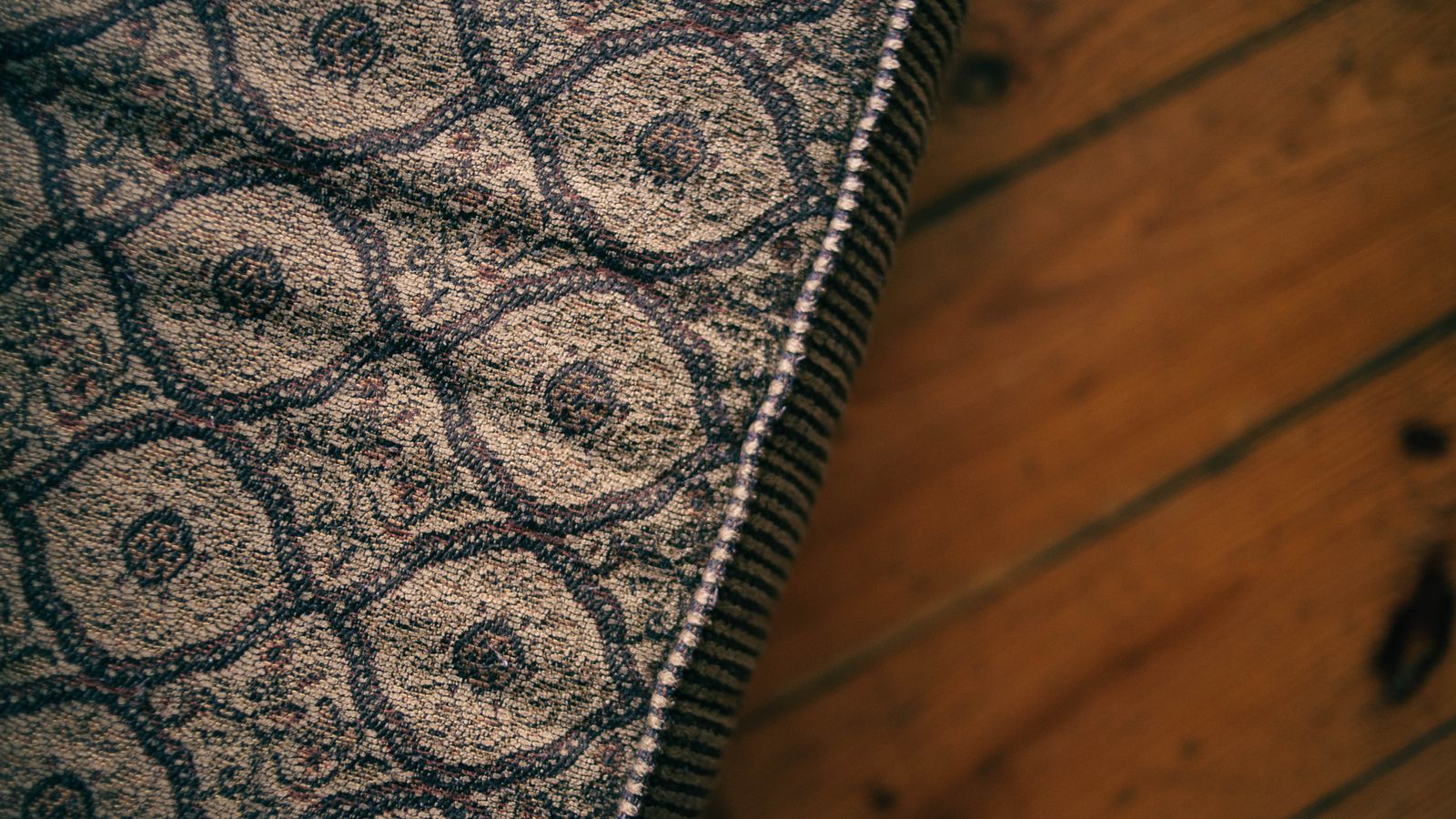 Corner of a patterned mattress on a wooden floor