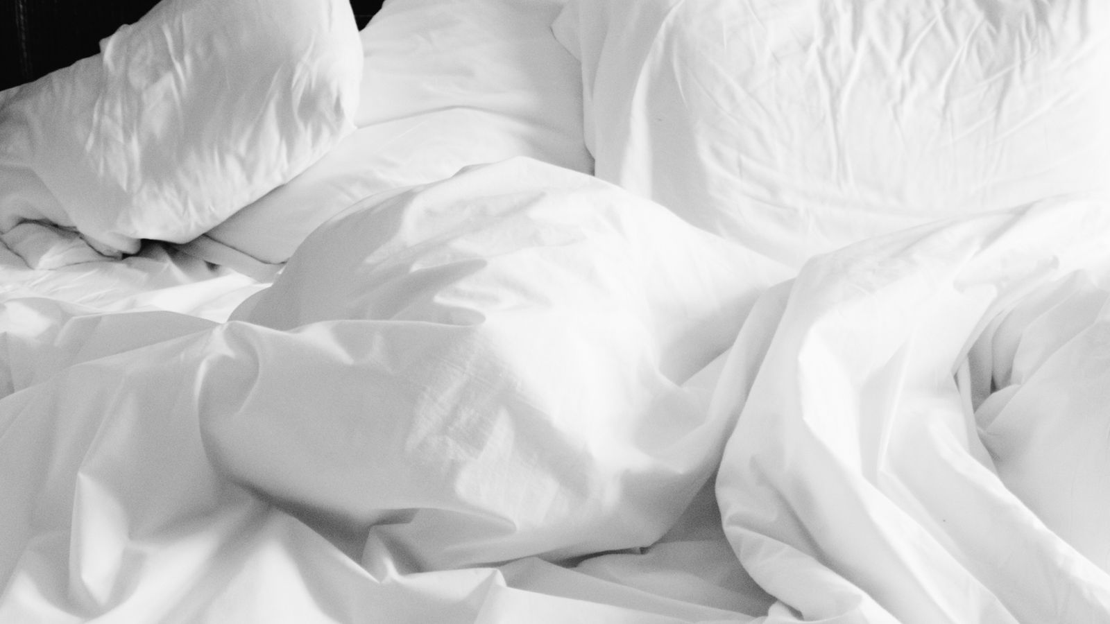 Rumpled white duvet on an unmade bed