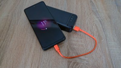 Smartphone charging from a portable power bank on a wooden table