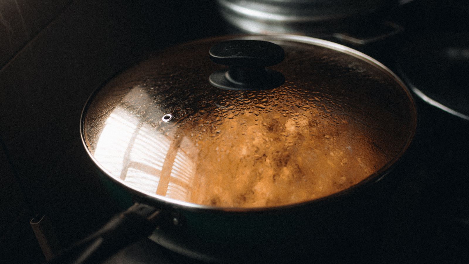 Steam on the glass lid of a pan cooking on a stove