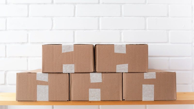 Taped cardboard boxes stacked on a wooden shelf