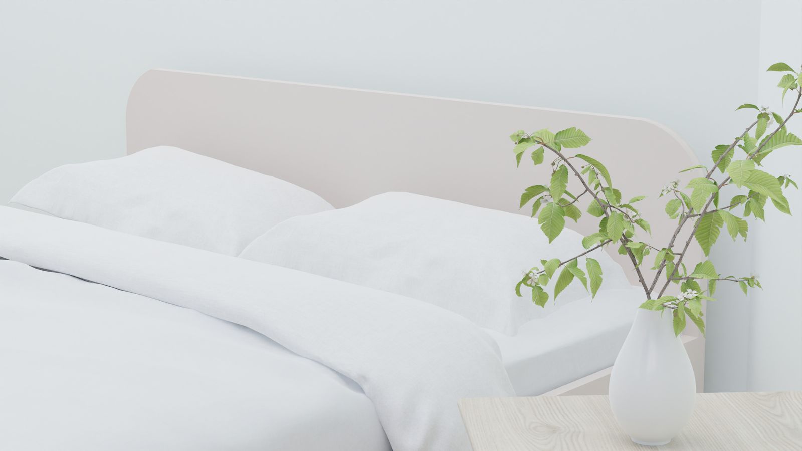 Bed with white linen beside a vase of greenery