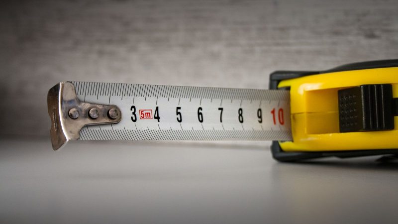 Yellow tape measure extended on a gray surface